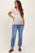 woman wearing a light beige short sleeve maternity top and blue jeans, showing her baby bump