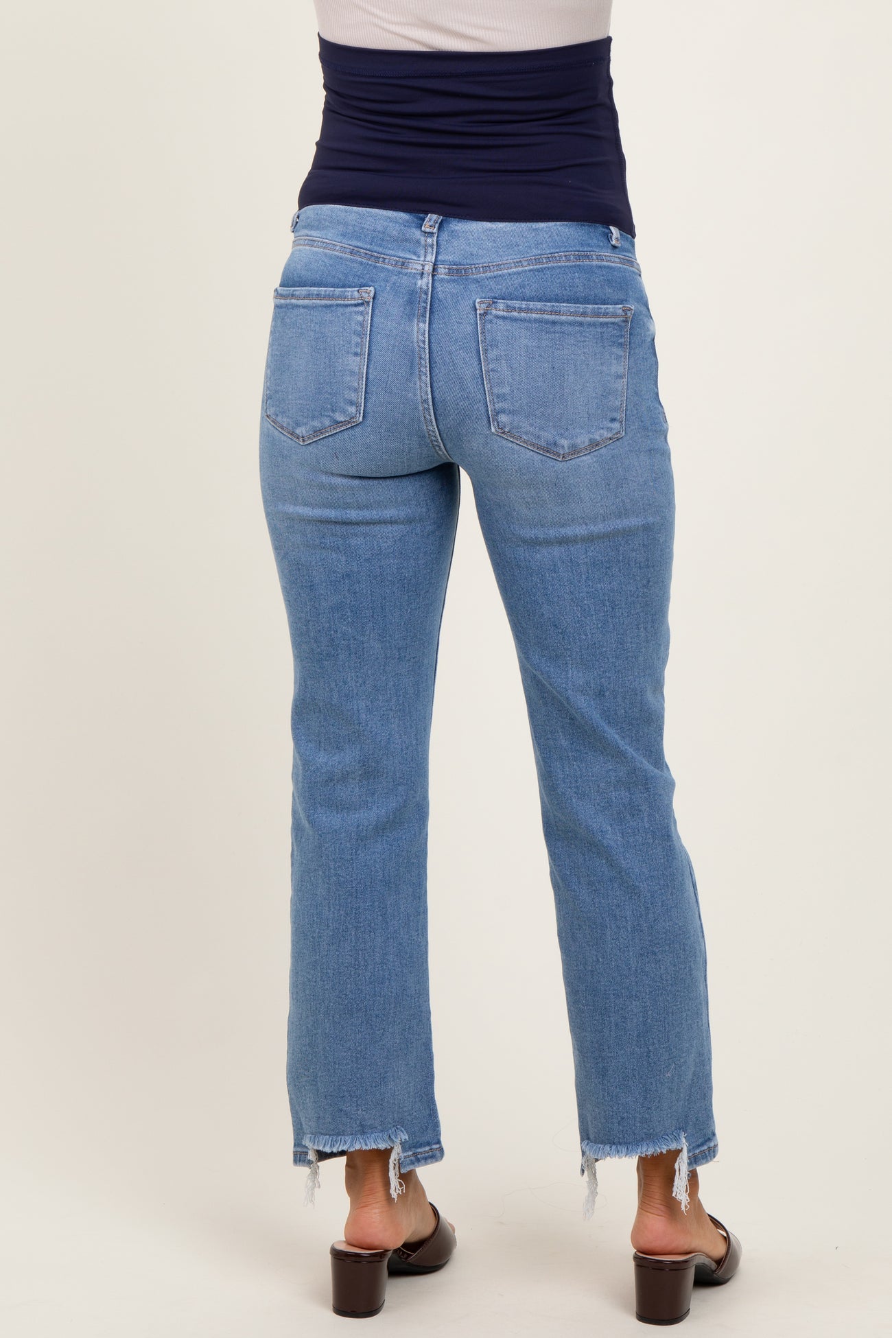 woman wearing light wash maternity jeans with a raw hem and back pockets, showcasing a relaxed fit
