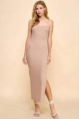 woman wearing a beige striped spaghetti strap maxi dress with a side slit and fitted silhouette