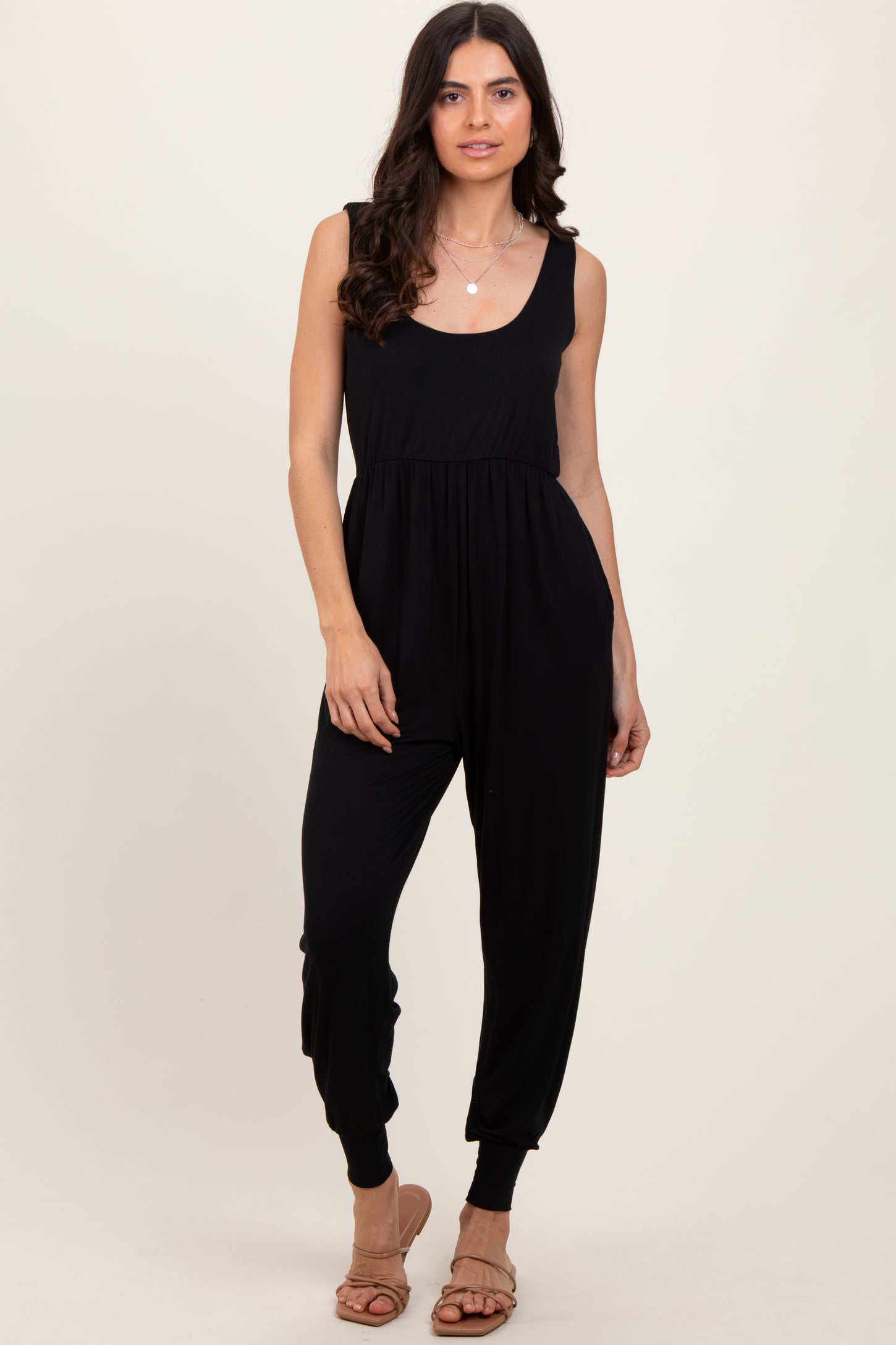 woman wearing a black sleeveless jumpsuit with a fitted bodice and relaxed jogger-style legs