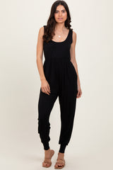 woman wearing a black sleeveless jumpsuit with a fitted bodice and relaxed jogger-style legs