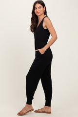 woman wearing a black sleeveless jumpsuit with pockets and a comfortable fit
