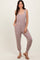 woman wearing a light taupe sleeveless jumpsuit with pockets and elastic cuffs, paired with brown sandals