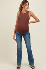 woman wearing a brown maternity tank top and blue flared jeans, showing a visible baby bump