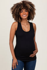 woman wearing a black ribbed maternity tank top and gently holding her baby bump