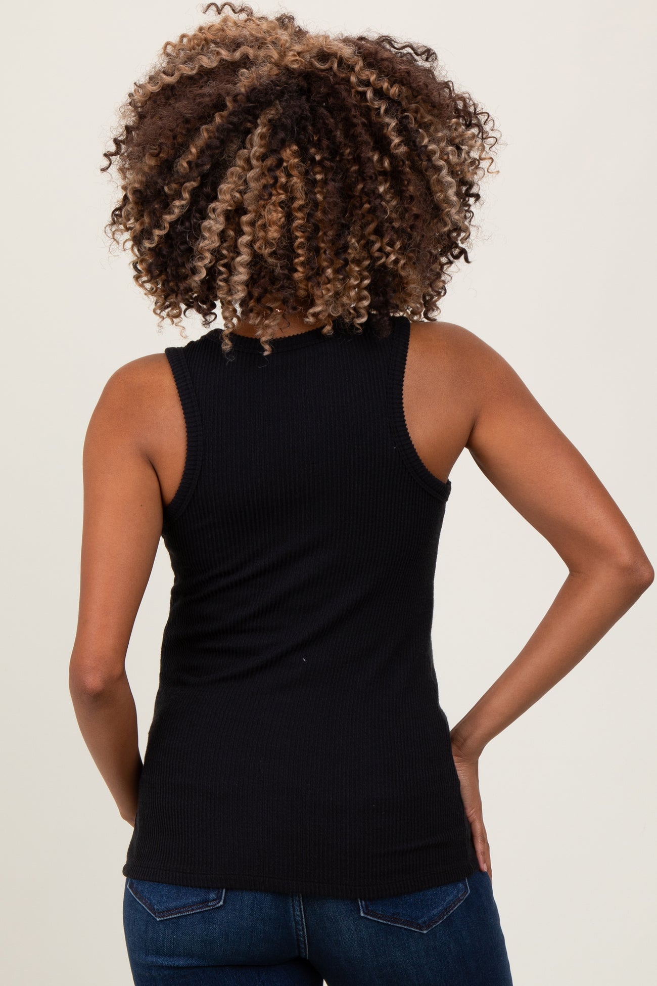woman wearing a black ribbed maternity tank top, seen from the back, paired with blue jeans
