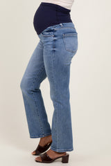 woman wearing light blue maternity jeans with a dark blue belly band and a visible baby bump