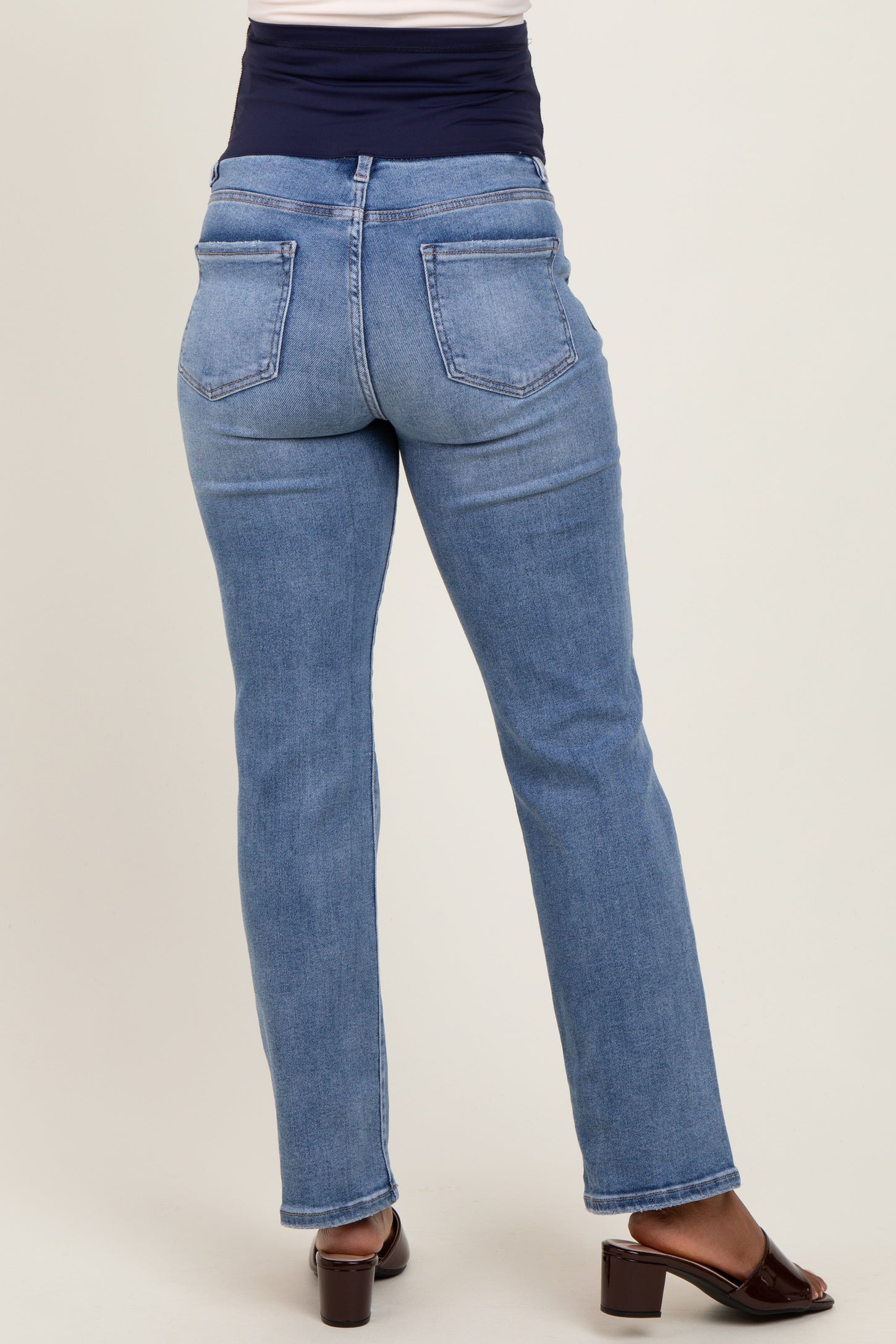 woman wearing light blue maternity jeans with a navy waistband, showing the back view and a comfortable fit