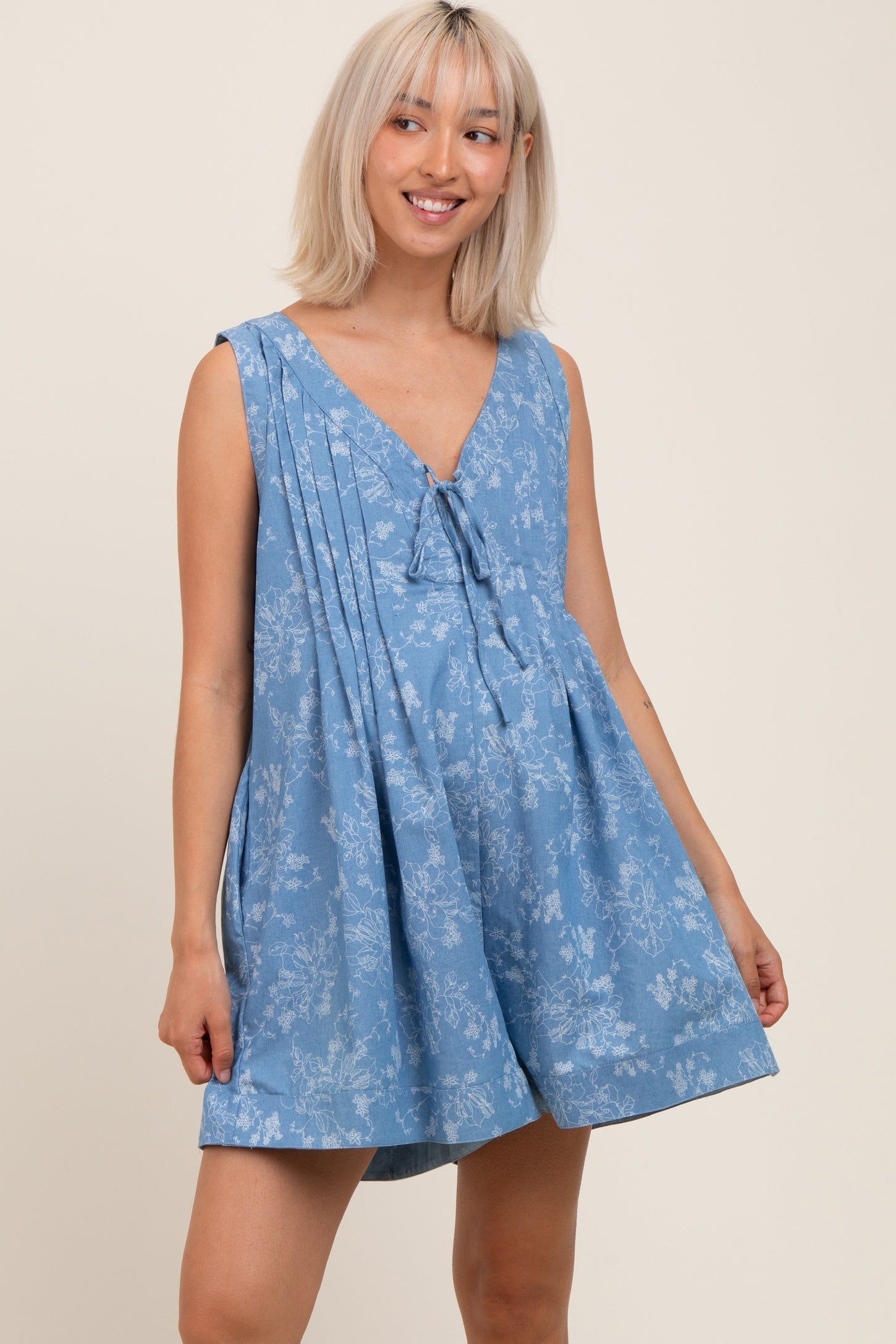 woman wearing a blue floral maternity dress with a v-neck and tie detail, showcasing her baby bump