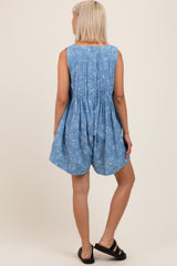 woman wearing a light blue maternity romper with a floral pattern and pleated back detail