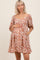 woman wearing a floral print maternity dress with a scoop neckline and three-quarter sleeves, holding her baby bump