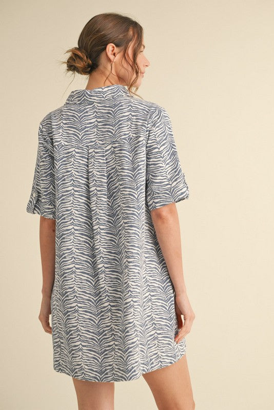 woman wearing a short-sleeve blue and white zebra print dress, viewed from the back