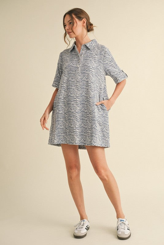 woman wearing a short-sleeve zebra print shirt dress with a collar and pockets, styled with white sneakers