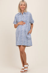 woman wearing a blue and white zebra print maternity dress with short sleeves and pockets, holding her baby bump