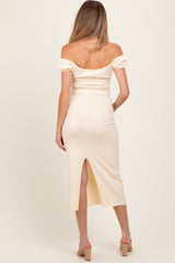 woman wearing a cream off-the-shoulder maternity dress with puff sleeves and a back slit