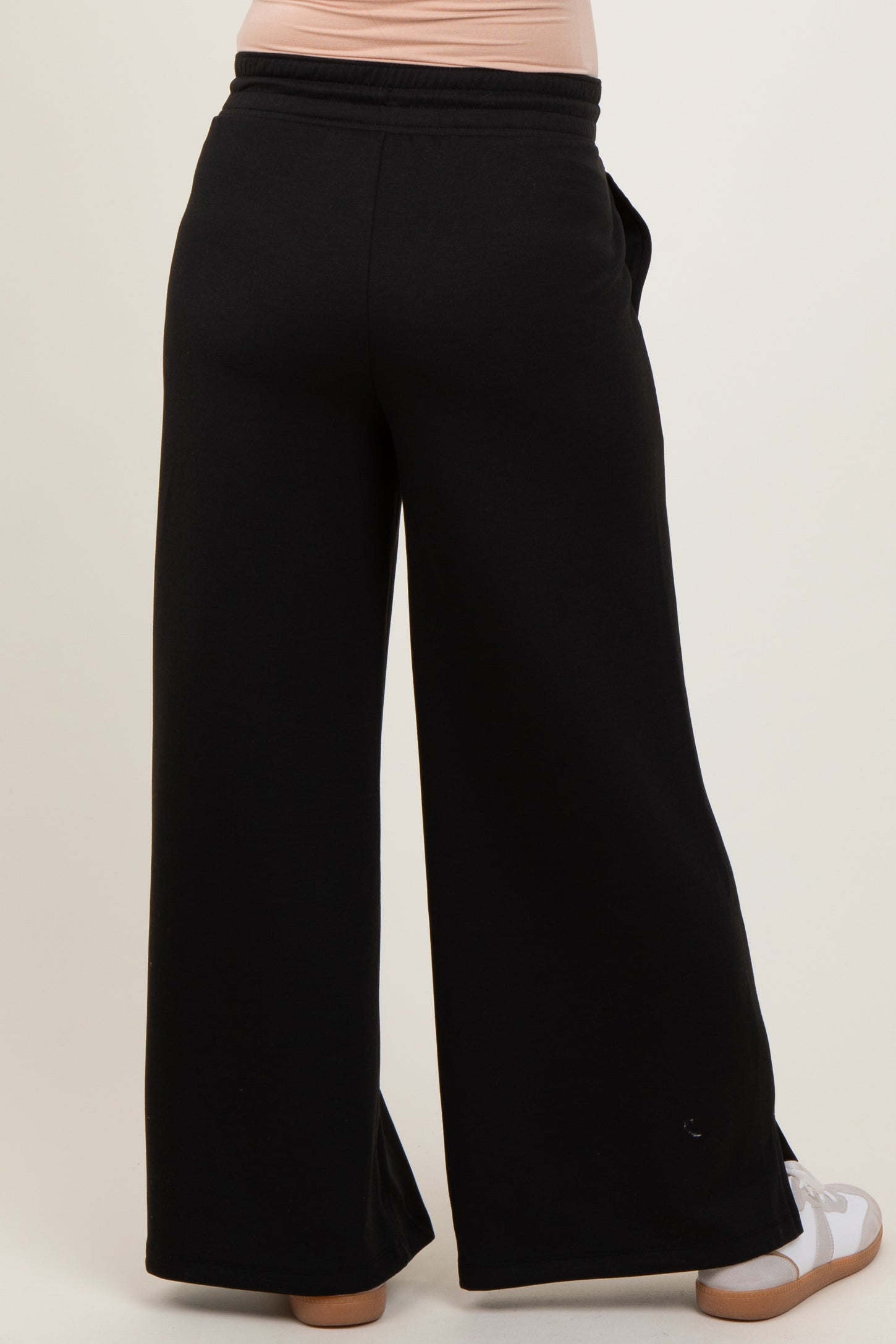 woman wearing black wide-leg maternity pants from the back, showing elastic waistband and relaxed fit
