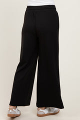 woman wearing black wide-leg pants, viewed from the back, paired with white sneakers