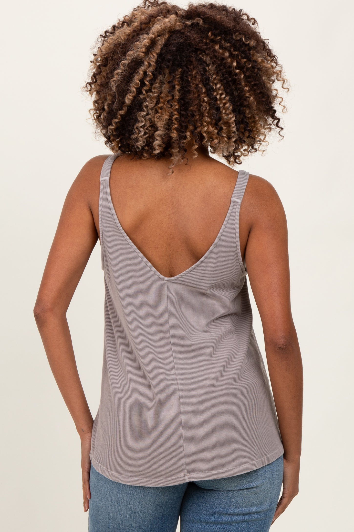 woman wearing a gray maternity tank top with a deep V-back, showing her back and curly hair