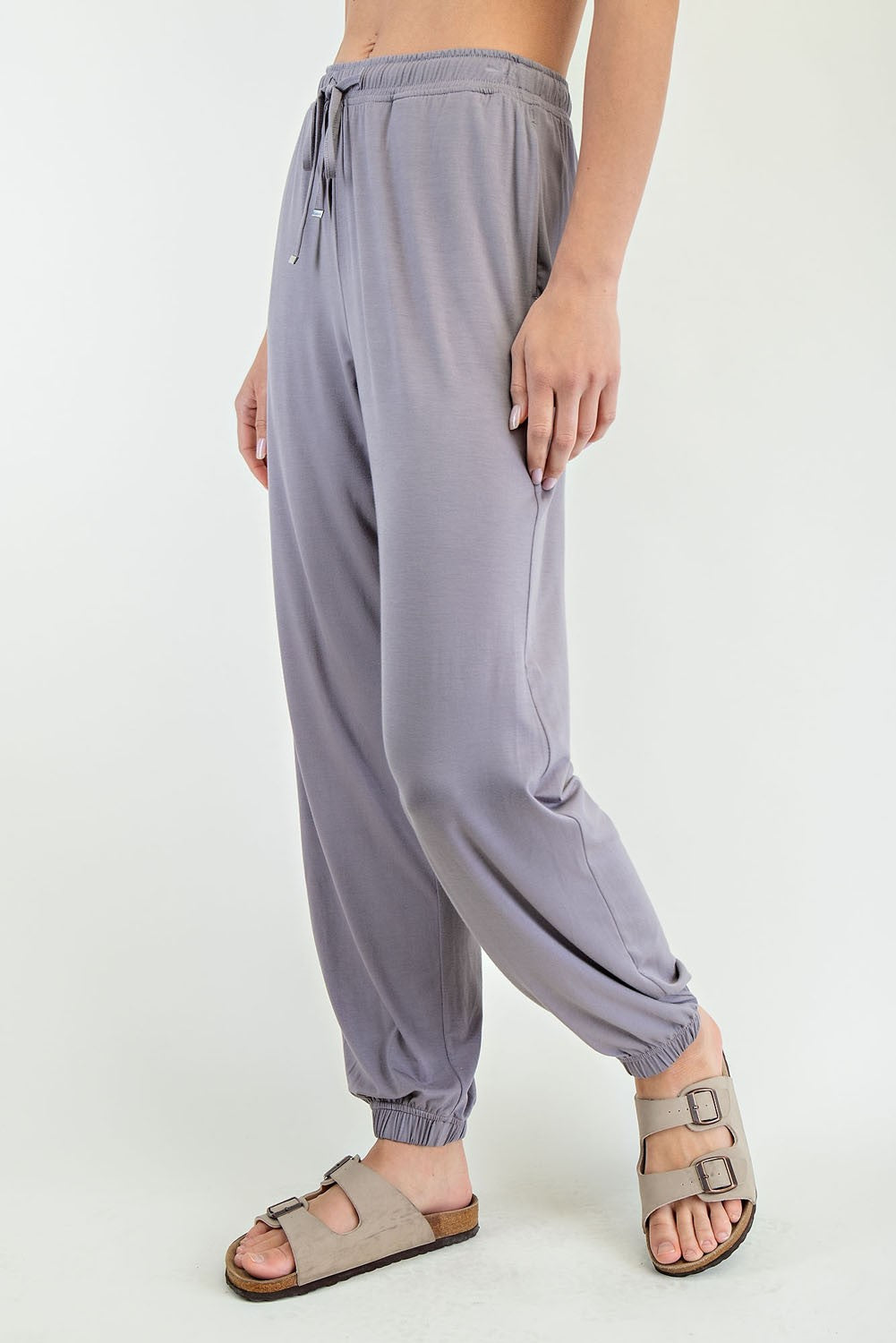 woman wearing light purple loose-fit jogger pants with an elastic waistband and cuffed ankles, paired with sandals