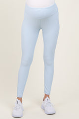 woman wearing light blue maternity leggings with a ribbed texture and a supportive waistband, paired with white athletic shoes