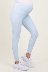 woman wearing light blue maternity leggings with a supportive belly band and white athletic shoes, showing baby bump