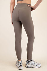 woman wearing form-fitting brown ribbed leggings and white athletic shoes, viewed from the back