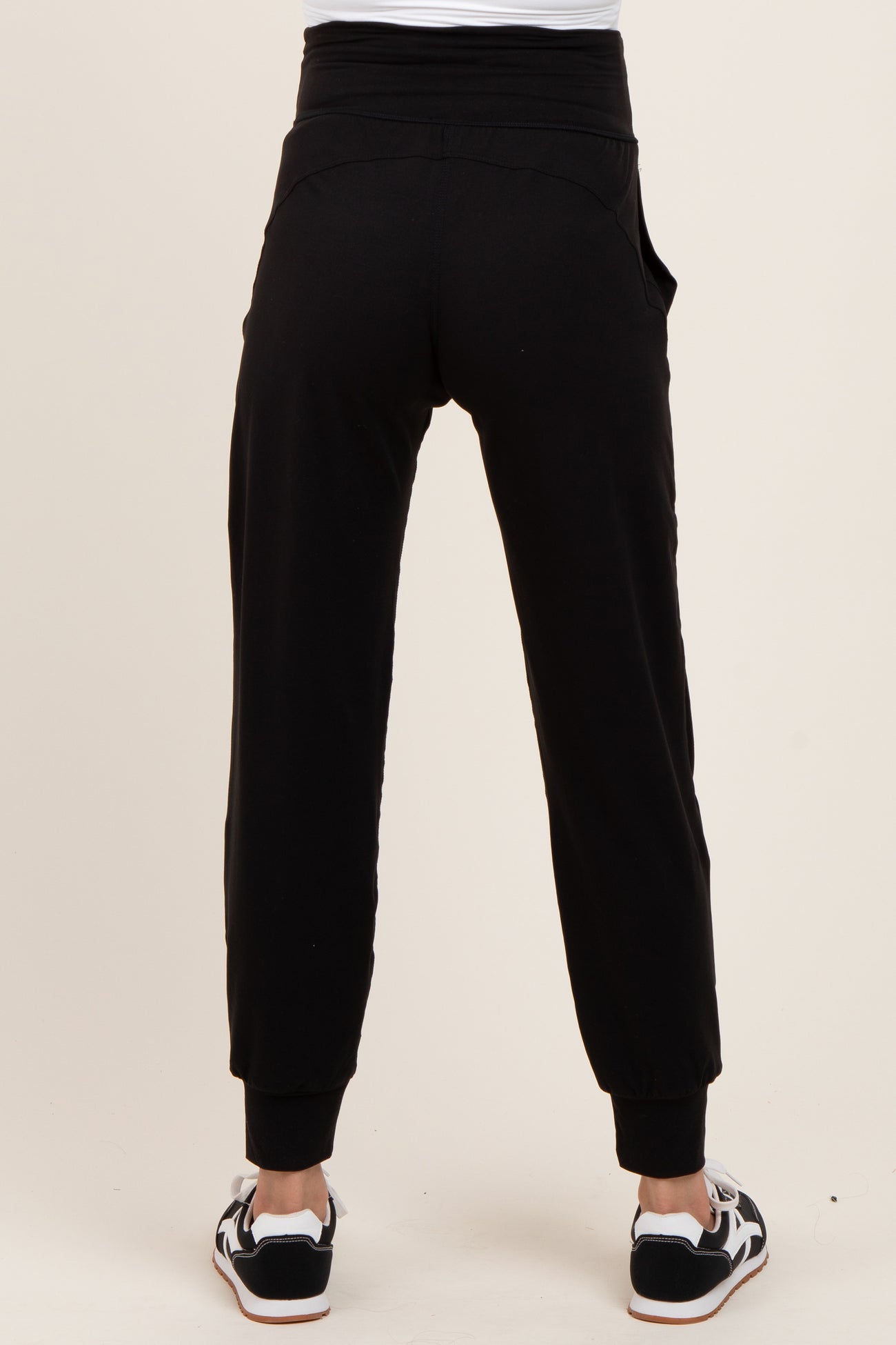 woman wearing black maternity joggers with a relaxed fit and cuffed ankles, viewed from the back