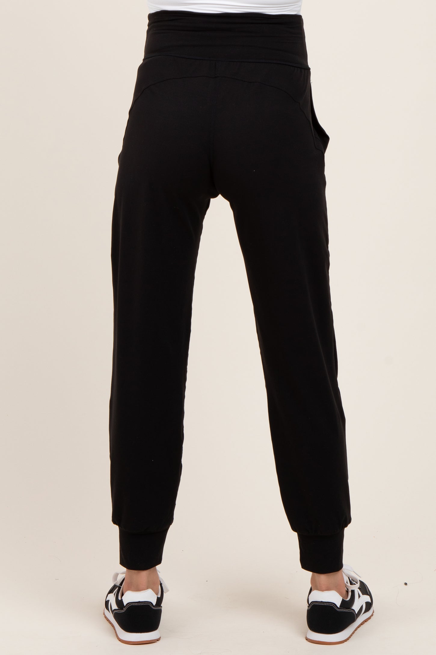 woman wearing black maternity joggers with a relaxed fit and cuffed ankles, viewed from the back