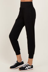 woman wearing black jogger pants with a high waist and cuffed ankles, paired with black athletic shoes