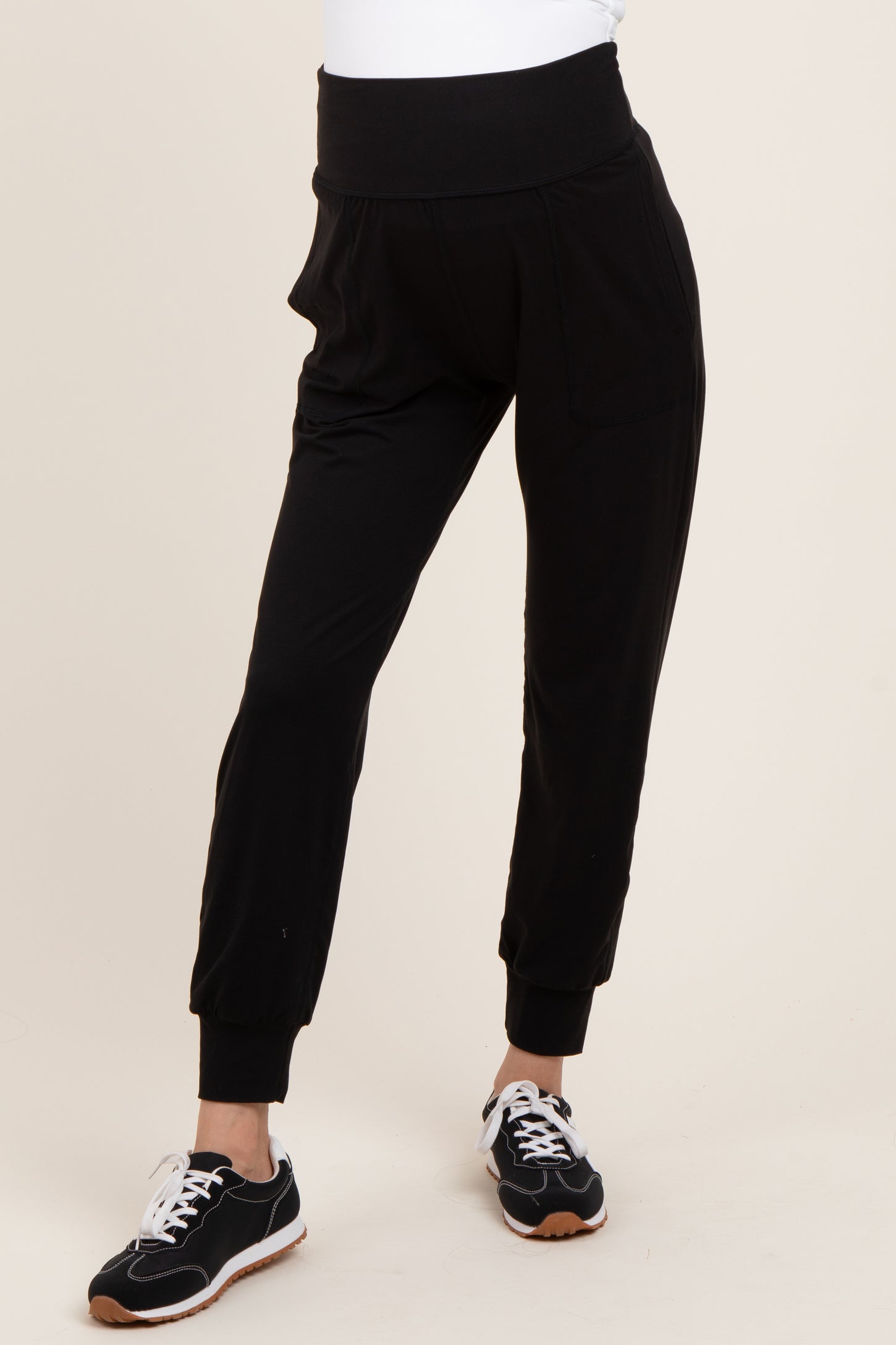 woman wearing black maternity joggers with a high waistband and side pockets, paired with sneakers