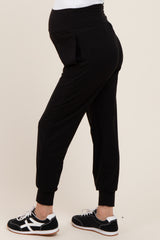 woman wearing black maternity joggers with a stretchy waistband and a visible baby bump