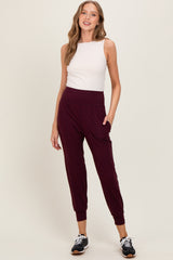 woman wearing a white sleeveless top and burgundy jogger pants with pockets