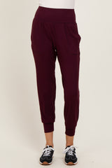 woman wearing burgundy jogger pants with side pockets and ribbed cuffs, paired with black sporty shoes