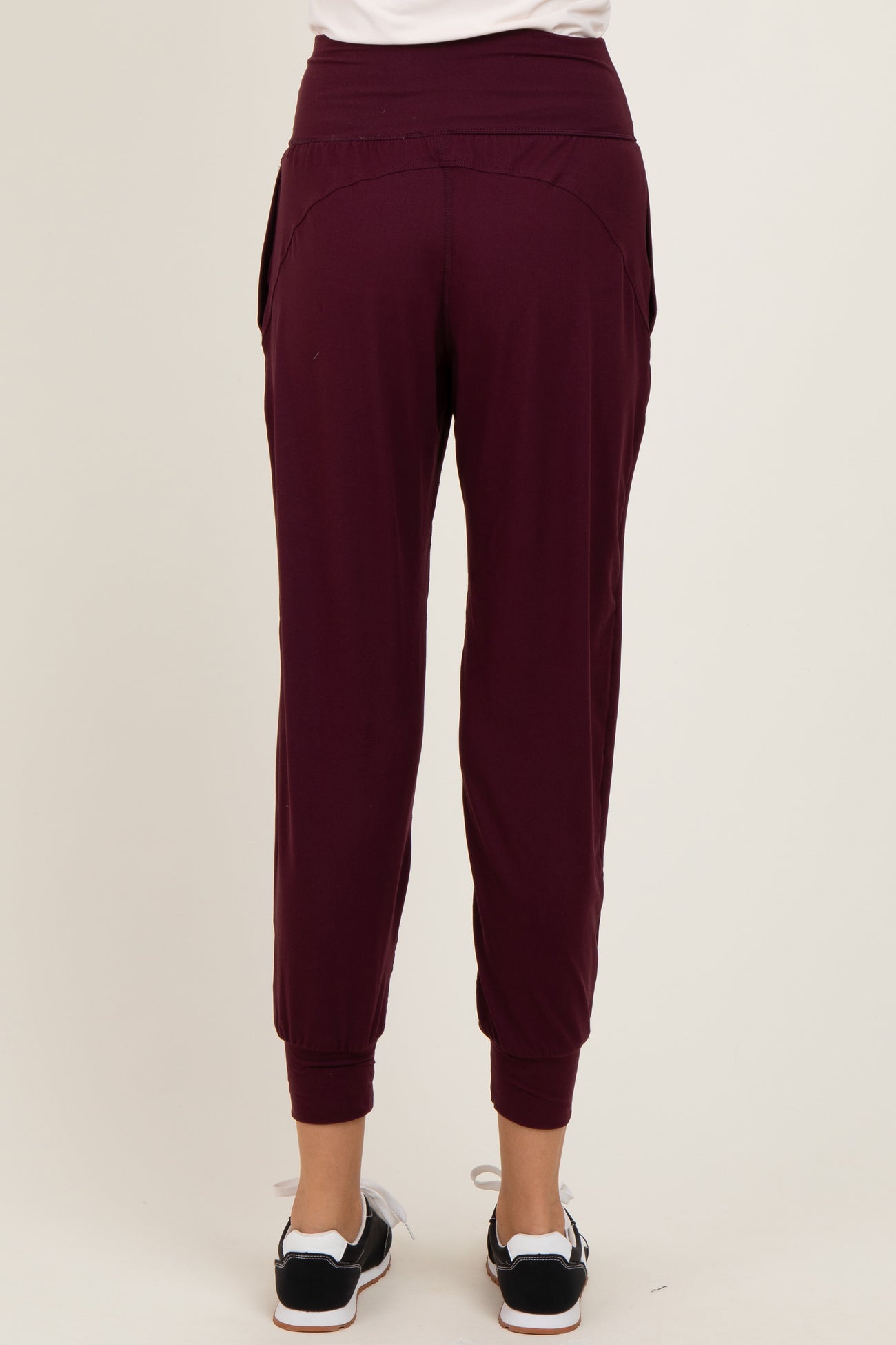 woman wearing burgundy tapered jogger pants with a comfortable waistband and side pockets, viewed from the back