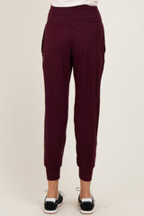 woman wearing burgundy tapered jogger pants with a comfortable waistband and side pockets, viewed from the back