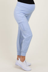 woman wearing light blue maternity joggers with pockets and a fitted waistband, showing her baby bump