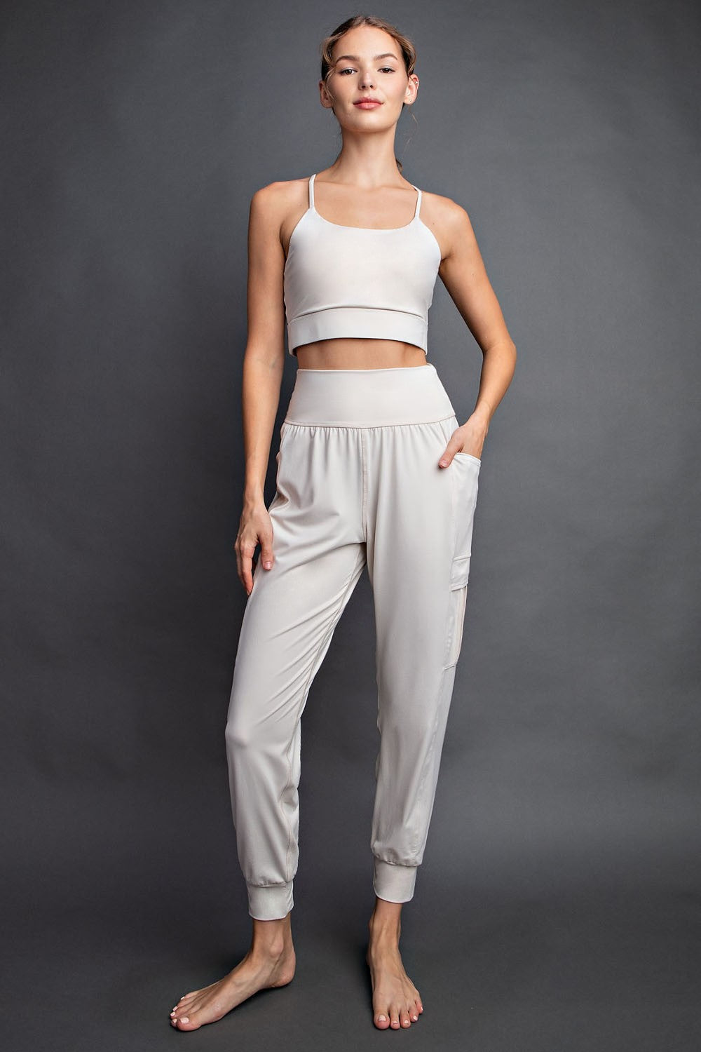 woman wearing a light gray crop top and matching jogger pants with side pockets