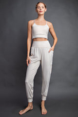 woman wearing a light gray crop top and matching jogger pants with side pockets