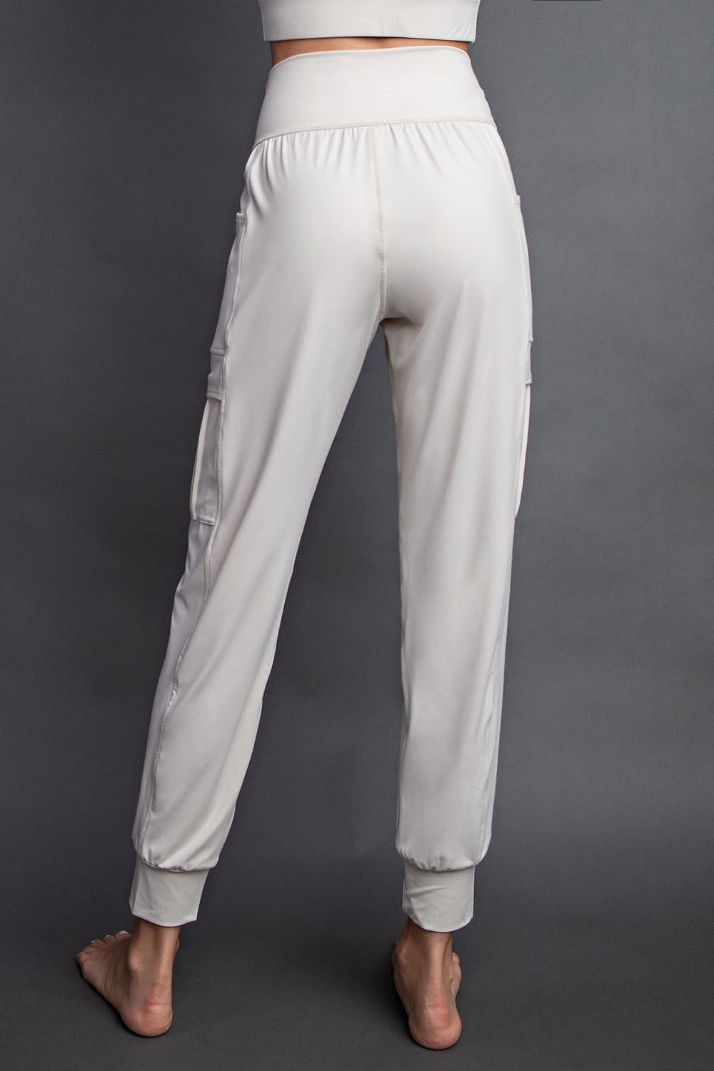 woman wearing cream-colored jogger pants with side pockets and elastic cuffs, shown from the back