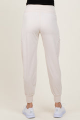 woman wearing light pink maternity cargo pants, showing the back view with elastic waistband and cuffed hems