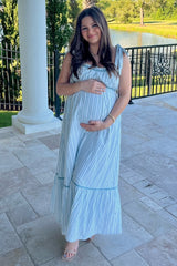 woman wearing a light blue and white striped maternity maxi dress and holding her baby bump