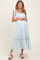 woman wearing a light blue and white striped maternity dress with tie straps and a flared hem, showcasing her baby bump