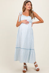 woman wearing a light blue striped maternity dress with tie straps and a visible baby bump