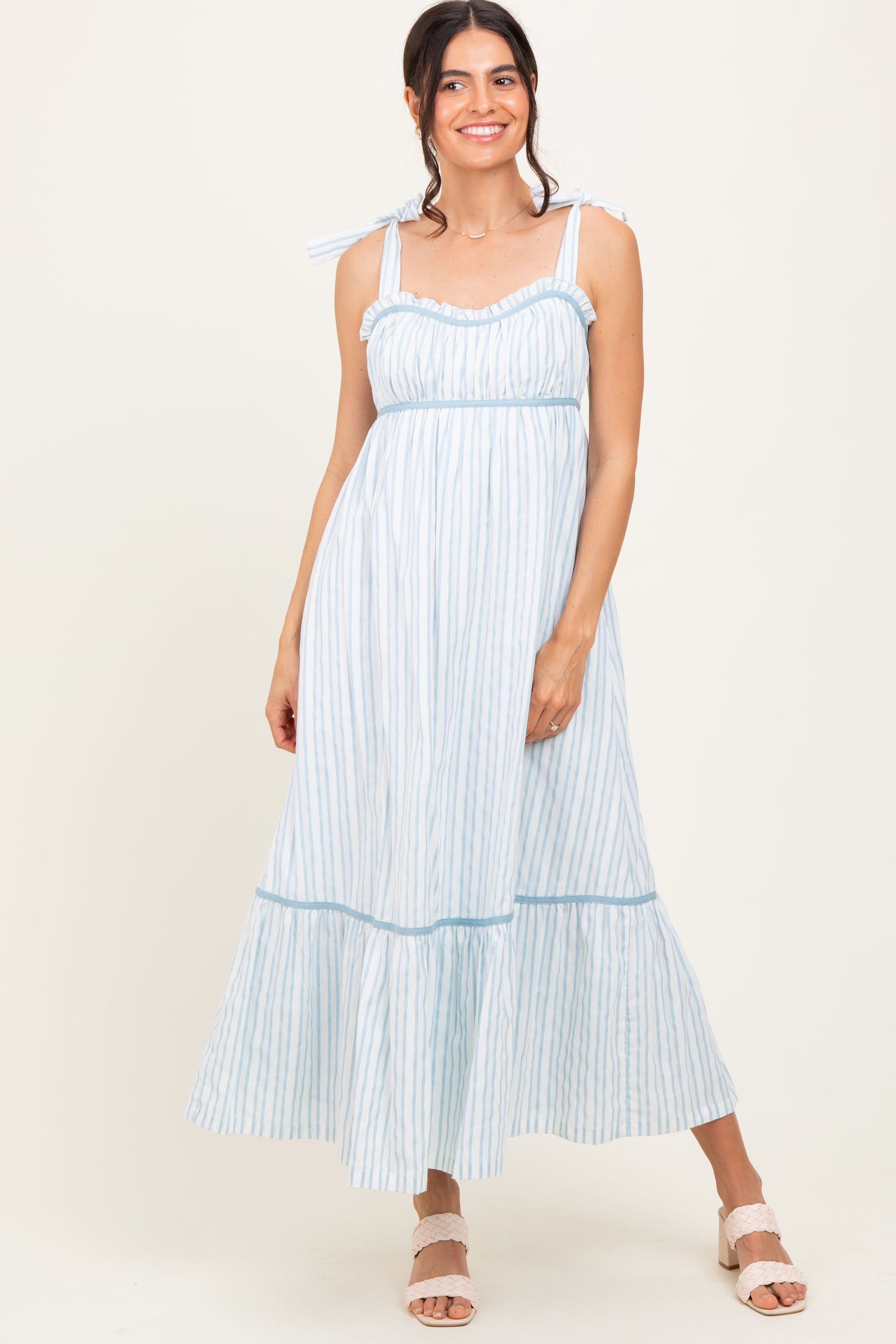 woman wearing a light blue striped maxi dress with ruffled straps and tiered hem