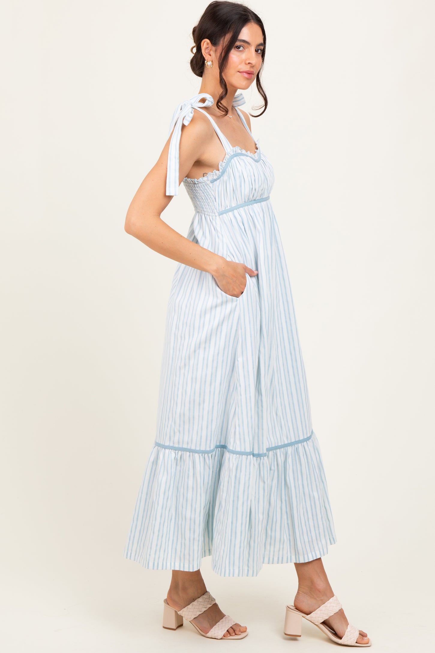 woman wearing a light blue and white striped maxi dress with tie straps and a tiered ruffle hem