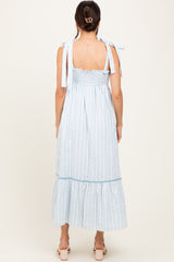woman wearing a light blue and white striped maxi dress with tie shoulder straps and a ruffled hem