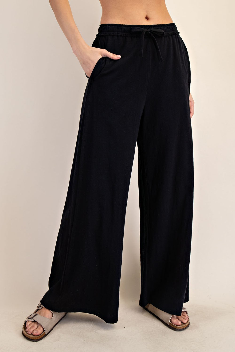 woman wearing black wide-leg pants with pockets and an elastic waistband, paired with sandals