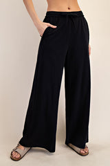 woman wearing black wide-leg pants with pockets and an elastic waistband, paired with sandals