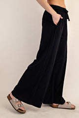 woman wearing black wide-leg pants with pockets and a drawstring waist, paired with light-colored sandals