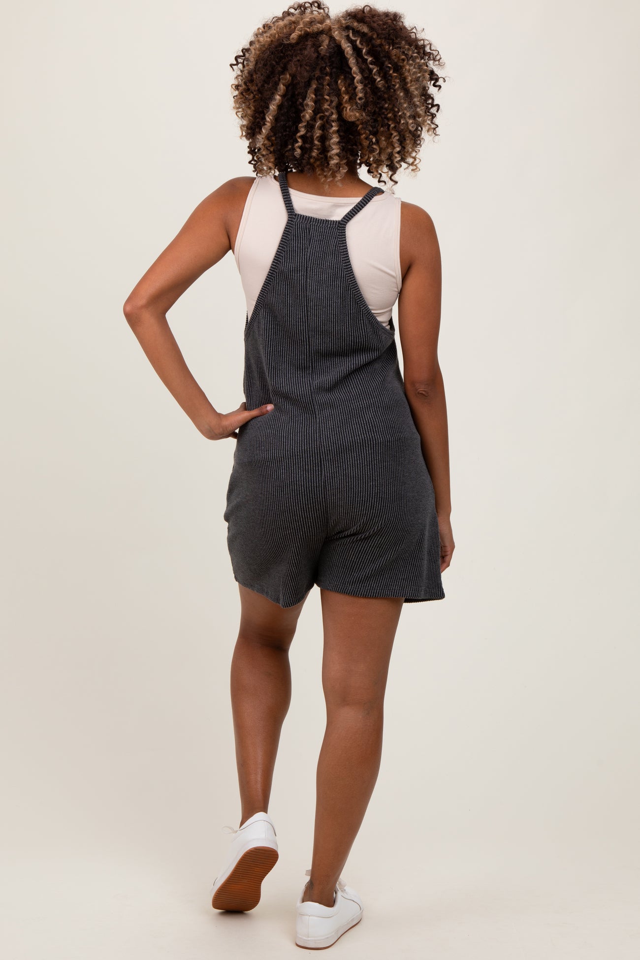 woman wearing a striped maternity romper with a fitted bodice and loose shorts, shown from the back